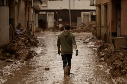 Un joven camina por una calle llena de barro en el centro de Paiporta durante los días siguientes a la dana.