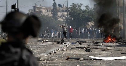 Jóvenes palestinos enmascarados arrojan piedras a la policía israelí.