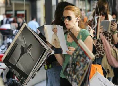 Una mujer lee uno de los libros de la instalación montada en la calle de Fuencarral con motivo del Día del Libro.