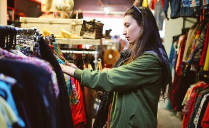 Una consumidora en una tienda de ropa de segunda mano.