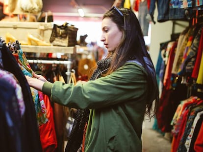 Una consumidora en una tienda de ropa de segunda mano.