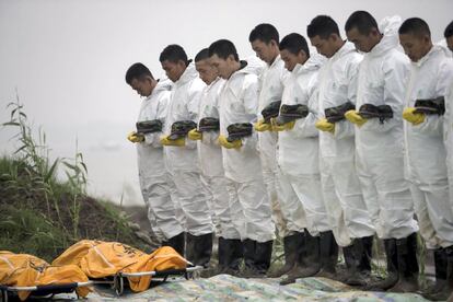 El equipo de rescate de las víctimas del barco turístico que se hundió en el río Yangtze guardan un minuto de silencio ante dos de los cuerpos recuperados.