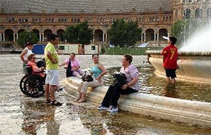 El calor llevó ayer a muchos sevillanos a refrescarse en las fuentes como la de la Plaza de España.