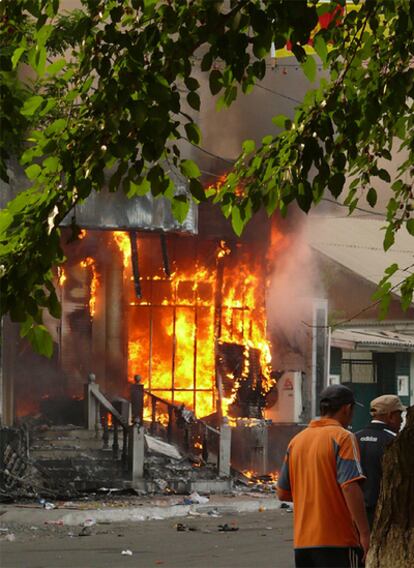 Dos hombres pasan ante un edificio en llamas en la ciudad de Osh (Kirguistán). Los violentos disturbios registrados la pasada madrugada en esa localidad del este de la ex república soviética han dejado al menos 17 muertos.