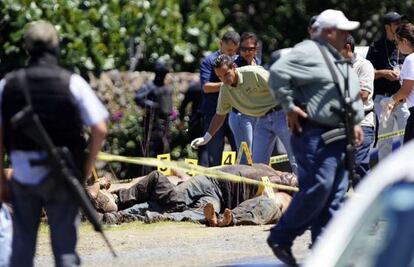Trabajadores forenses realizan el levantamiento de los 17 cadáveres este domingo.
