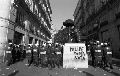 Agentes antidisturbios de la Policía Nacional junto al monumento del Oso y el Madroño en la Puerta del Sol de Madrid, donde se lee la pintada "Felipe, toma nota", durante la huelga general del 27-E de 1994.