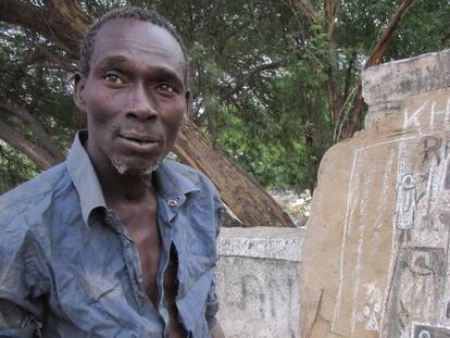 Pape Diop, junto a algunos de sus dibujos en el muro del cementerio de la Medina, en Dakar.