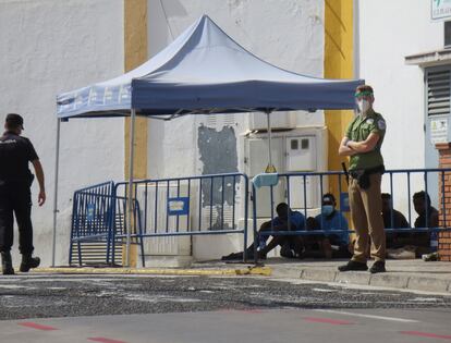 Un policía y un guarda de seguridad vigilan a un grupo de inmigrantes indocumentados que saltaron la valla de Melilla en agosto del año pasado.