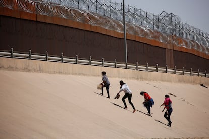 Migrantes caminan hacia el muro fronterizo luego de cruzar la frontera en El Paso, Texas