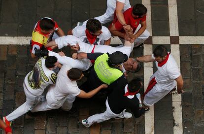 Varias personas socorren a un herido durante el tercer encierro de San Fermín 2016.