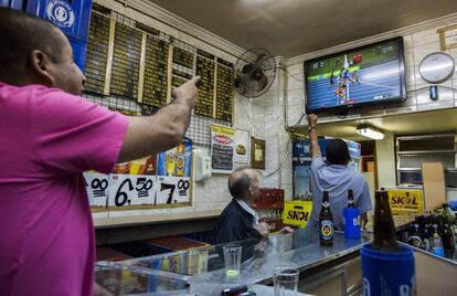 Clientes en un bar de Río observan la carrera de los 100 metros.