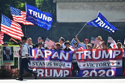 Simpatizantes del presidente Donald Trump ondean banderas cerca del hotel en el que se hospeda el mandatario en Tokio.