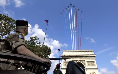 Un soldado observa como una formación de Alphajets traza con su estela los colores de la bandera francesa sobre el Arco del Triunfo de París.