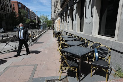 Un hombre con mascarilla pasa junto a una terraza cerrada de un bar en Madrid el 29 de abril.