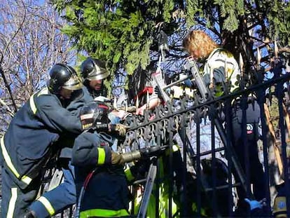 Bomberos y un médico del Samur intentan liberar al hombre que quedó atrapado en la valla del Retiro.