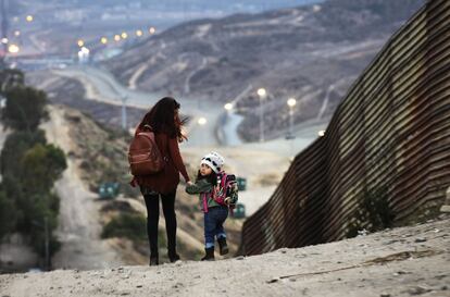 Una mujer y su hija pasean junto a la frontera con México en Tijuana.