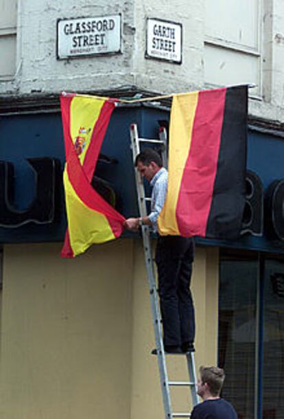 Un escocés cuelga las banderas española y alemana en Glasgow.