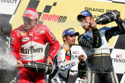 El ganador, Loris Capirossi, celebra su victoria junto con Max Biaggi, segundo, y Makoto Tamada, tercero en el Moto GP.