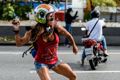 Una opositora se enfrenta con piedras a la policía antidisturbios durante la marcha contra el presidente Nicolás Maduro el 1 de mayo de 2017, en Caracas.