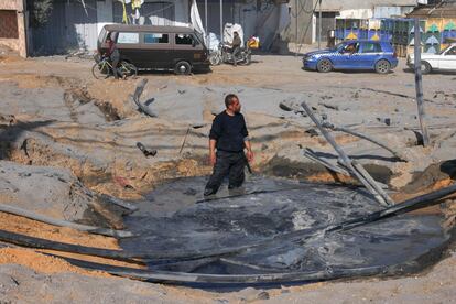 Un palestino se introduce en el interior de un cráter lleno de agua tras una ataque israelí en una carretera entre Rafah y Jan Yunis, este sábado.