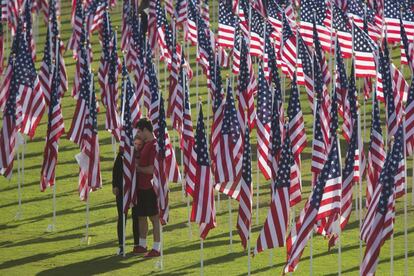 Una pareja asiste al 'Campo del Valor', evento en el que se colocan banderas con la bandera estadounidense para honrar a los veteranos de guerra y a los que siguen en servicio militar, en Orange, California (EE UU).