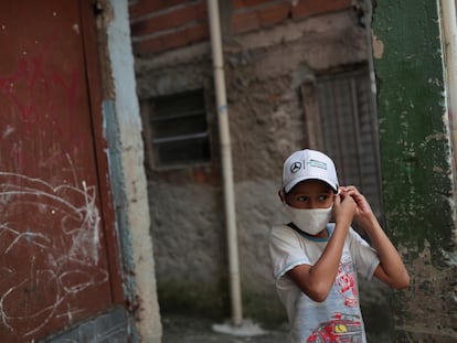 Criança ajusta máscara na favela de Paraisópolis, em São Paulo.