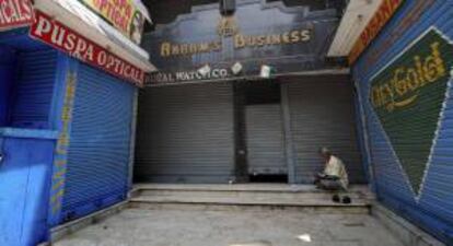 Un hombre lee junto a unos comercios cerrados durante una huelga en la India. EFE/Archivo