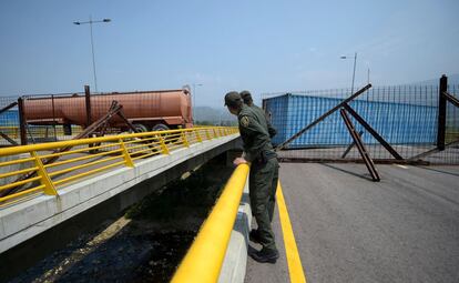Dos militares colombianos observan el bloqueo en el puente de Tienditas, que conecta Cúcuta (Colombia) con Táchira (Venezuela), el 6 de febrero. El Ejército venezolano ha colocado en medio de la vía un camión cisterna y contenedores de carga para evitar la llegada de ayuda humanitaria desde Colombia.
