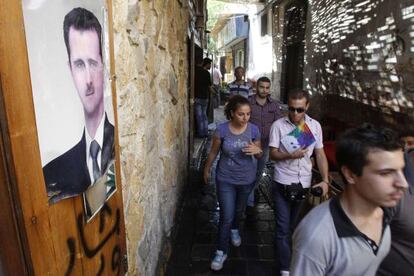 Unos sirios caminan en el centro de Damasco, ante un retrato de Bachar el Asad.