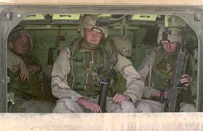 Tres soldados estadounidenses, sentados en un vehículo acorazado durante unas maniobras en el desierto de Kuwait.