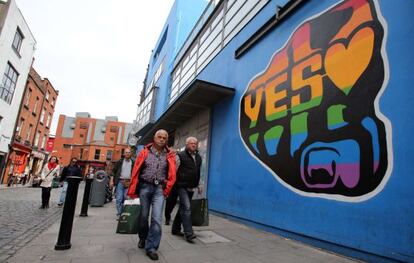 Ciudadanos de Dublín pasan por delante de un cartel a favor del sí en el referendum sobre el matrimonio gay.