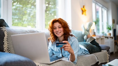 Una chica comprando tumbada en el sofá de su casa.
