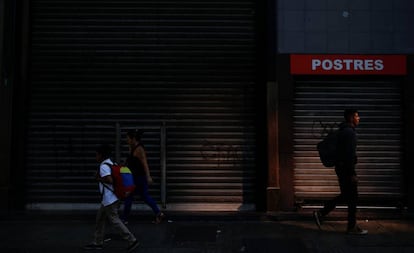 Tres personas pasan por delante de un restaurante cerrado por el apagón.