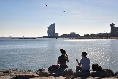 Una parella pren el sol a la platja, aquest dilluns.