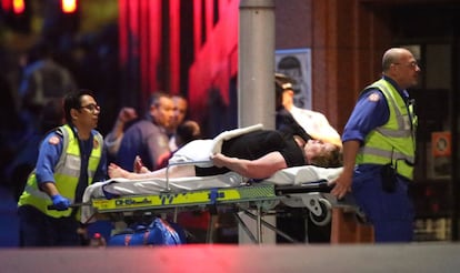 Almenys quatre persones han resultat ferides en l'operació policial per acabar amb el segrest per part d'un clergue musulmà d'un cafè en el centre de Sídney. En la imatge, personal sanitari trasllada a un dels ferits.