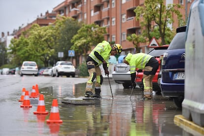 Dos operarios desatascan una alcantarilla, el sábado en Huesca.