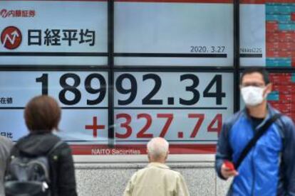 Peatones contemplando una tabla con cotizaciones bursátiles, en Tokio.