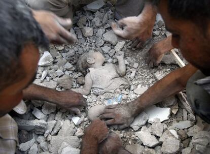 Varios hombre limpian el cadáver de un bebe asesinado durante una reciente huelga de la fuerza aérea siria en Azaz, al norte de Alepo. Imagen del15 de agosto del 2012.