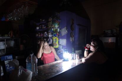 Flor Dalisa Contreras (L) habla con Virginia Rivas en una cafetería durante el apagón.