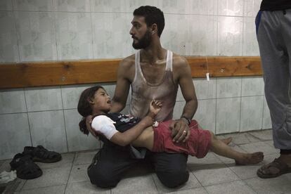 Un palestino sostiene una niña herida en el bombardeo israelí a una escuela dirigida por la ONU.