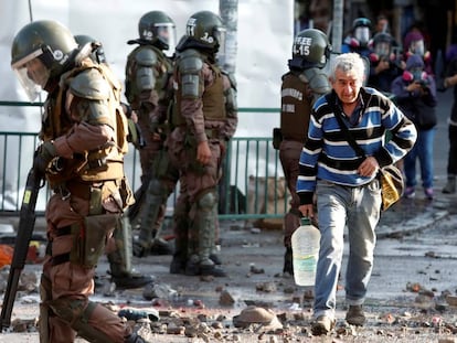 Un hombre camina entre policías antimotines durante las protestas registradas en Santiago el 18 de noviembre pasado.