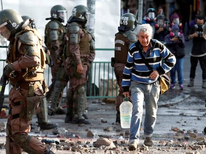 Un hombre camina entre policías antimotines durante las protestas registradas en Santiago el 18 de noviembre pasado.