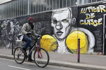Un ciclista pasa por delante de un mural que hace referencia a las protestas de los 'chalecos amarillos'.