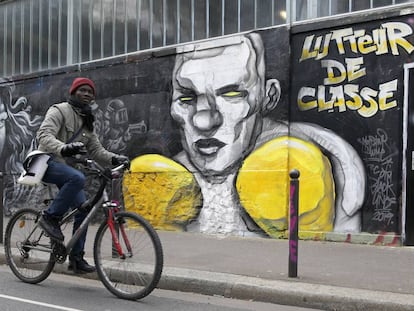 Un ciclista pasa por delante de un mural que hace referencia a las protestas de los 'chalecos amarillos'. 