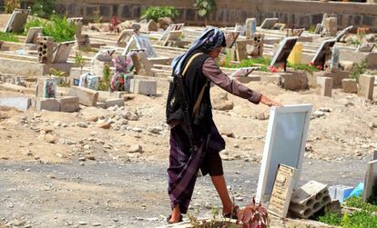 Un hombre armado observa un retrato de un familiar junto a su tumba en Saná (Yemen), este martes.