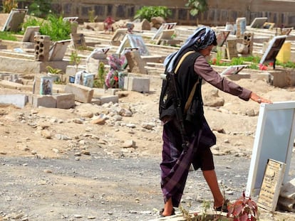 Un hombre armado observa un retrato de un familiar junto a su tumba en Saná (Yemen), este martes.