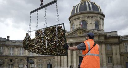 Un operario retira los candados de las barandillas del Pont des Arts de París ya que pueden causar daños y riesgo para la seguridad.