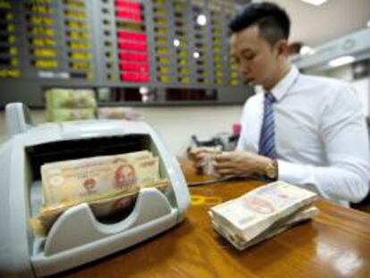 Un empleado bancario prepara billetes para entregar a los clientes en un banco de Hánoi, Vietnam. EFE/Archivo