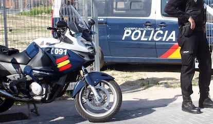 Un agente de la Policía Nacional, junto a dos vehículos policiales, en una imagen de archivo.