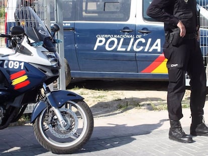 Un agente de la Policía Nacional, junto a dos vehículos policiales, en una imagen de archivo.